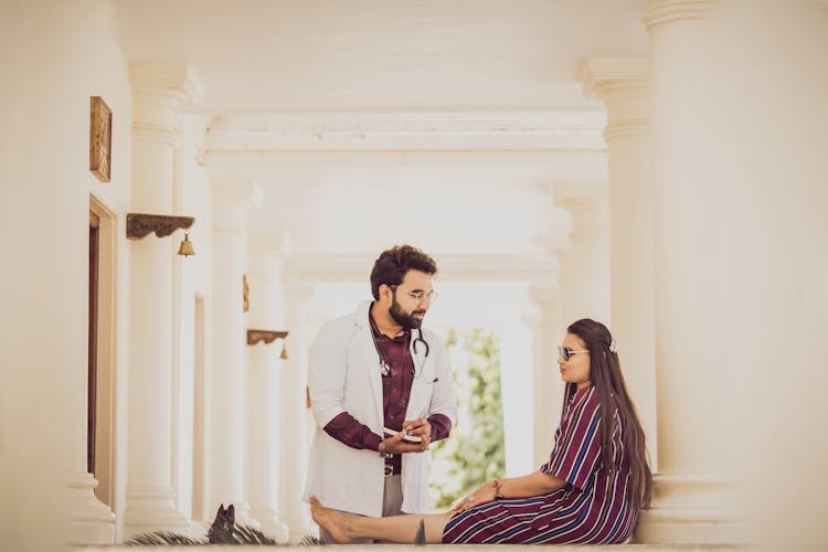 Doctor Talking To Woman Sitting On Ground