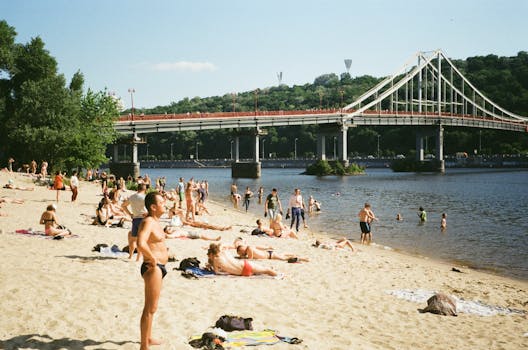 People enjoy a sunny day on the sandy beach by the Dnieper River in Kyiv, near Park Bridge.