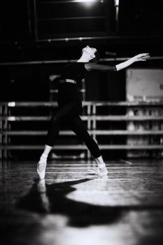 Elegant ballerina in motion during a rehearsal, captured in black and white, showcasing grace and poise.