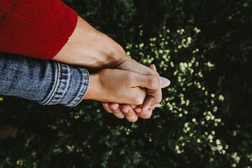 Free A close-up of two people holding hands outdoors, emphasizing connection and warmth. Stock Photo