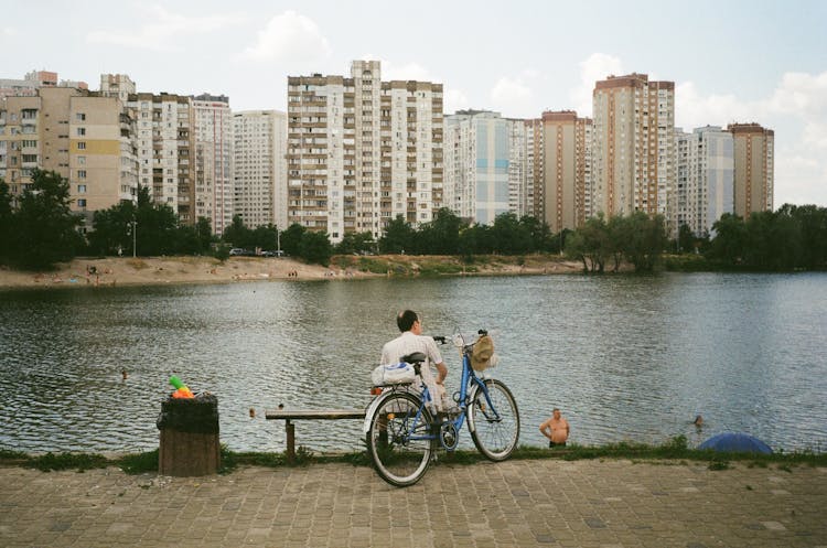 People Relaxing By The Lake In City