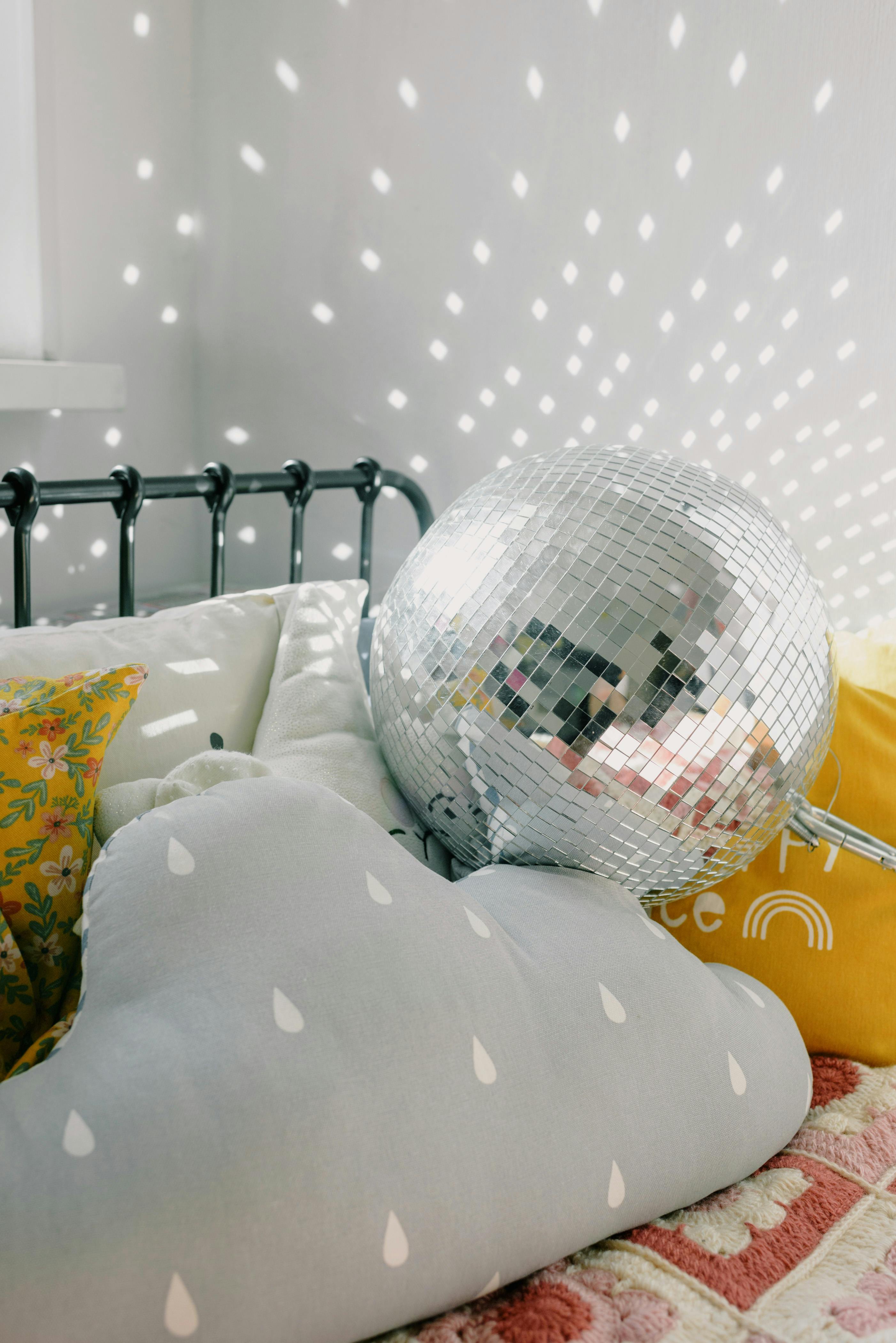 A bright bedroom featuring colorful cushions and a reflective disco ball.