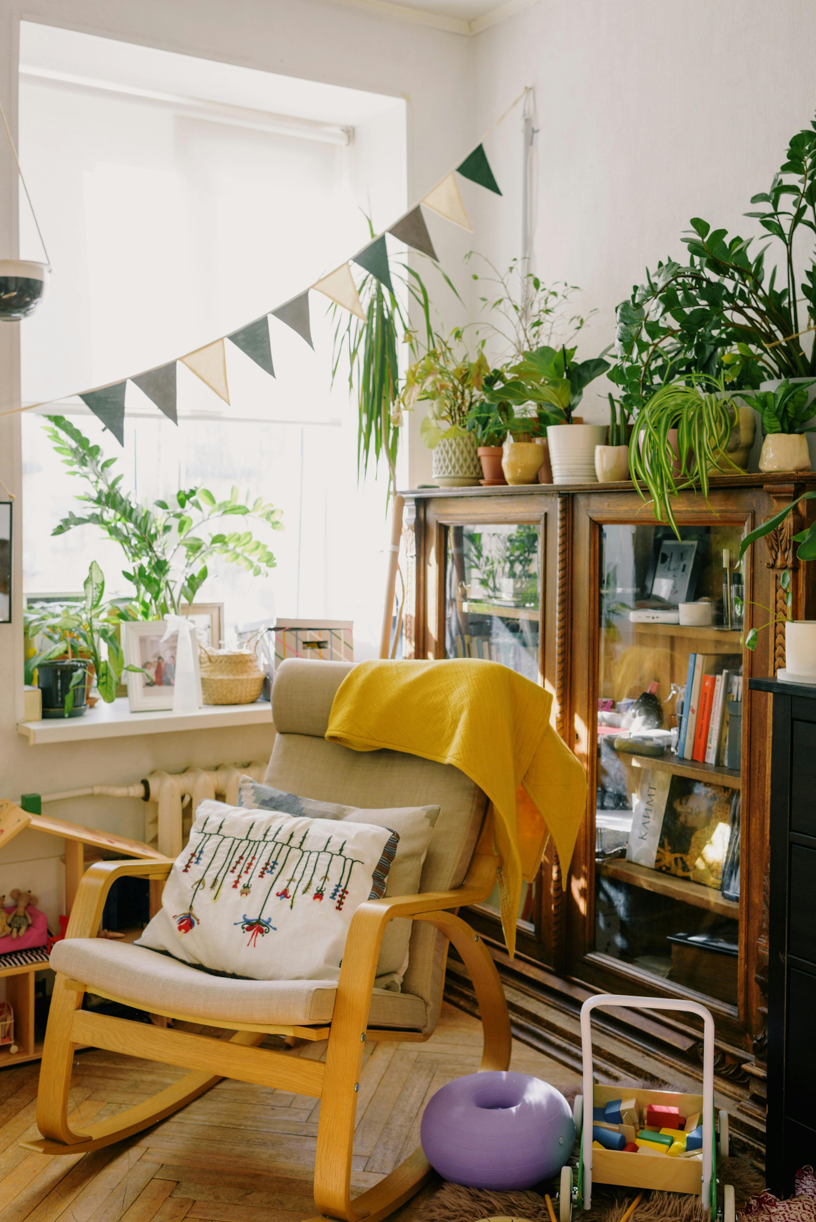 A cozy living room with sunlight, plants, and a vintage armchair, perfect for relaxation.