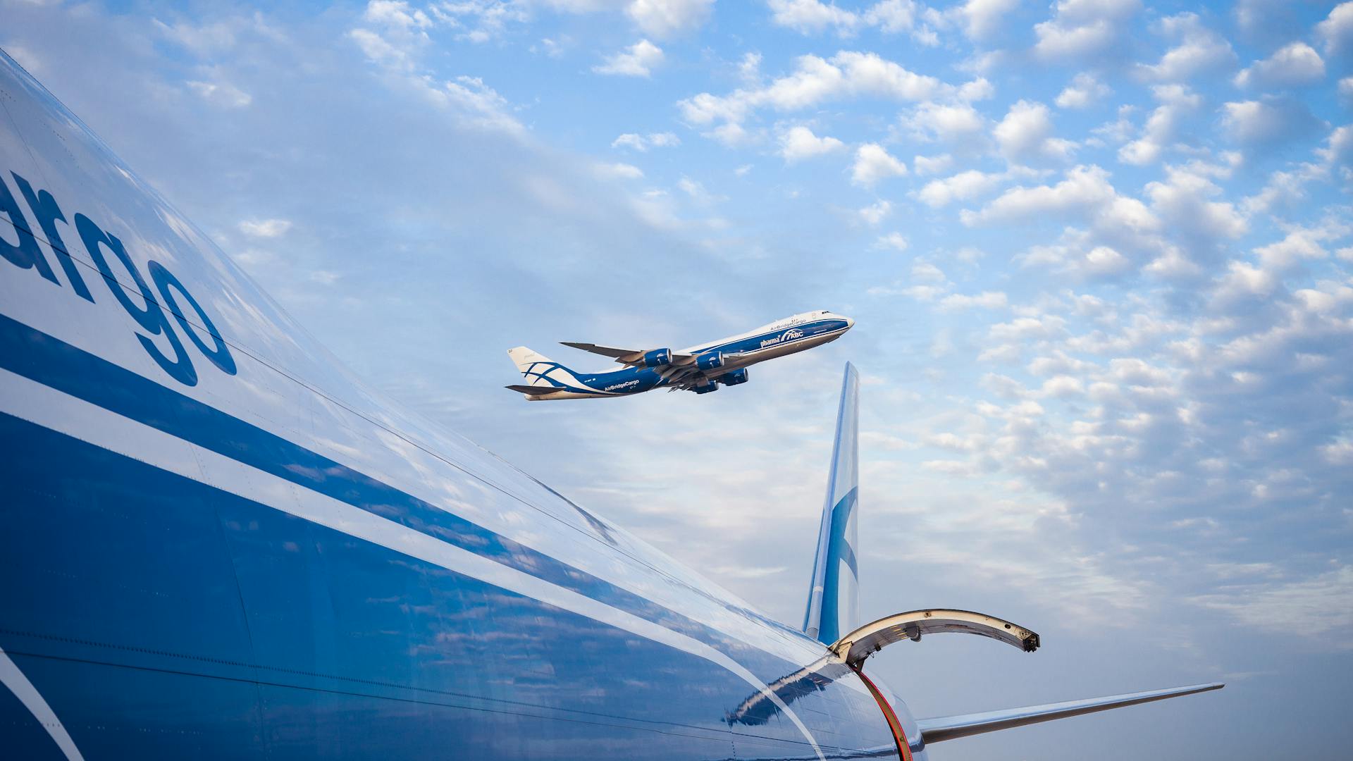 Cargo airplanes in flight under a bright blue sky with scattered clouds. Perfect for travel and aviation themes.