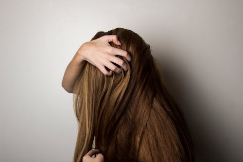 Bezpłatne Zdjęcie Kobiety Zakrywającej Twarz Włosami. Zdjęcie z galerii
