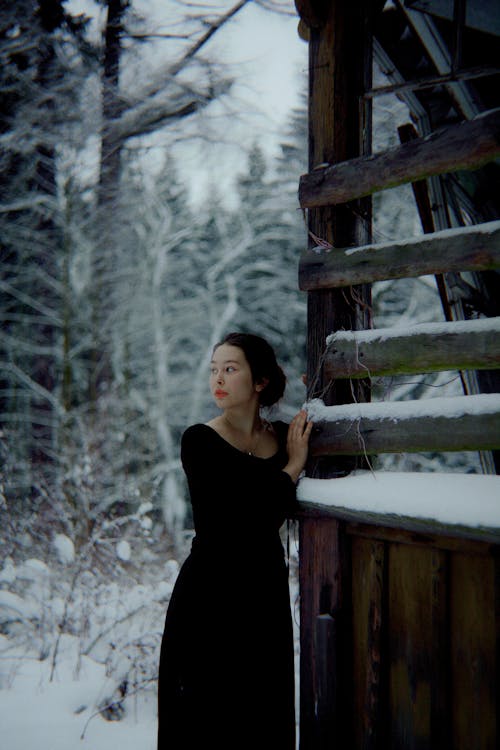 Woman in Black Dress holding on to a Log House 