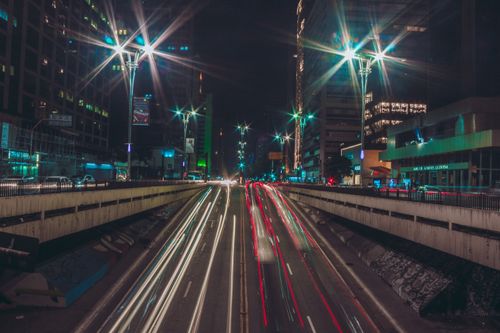 Free Vibrant night cityscape featuring dynamic light trails of traffic on a bustling urban street. Stock Photo
