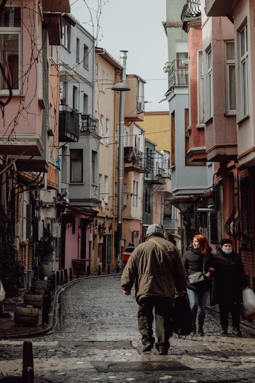 People Walking on the Narrow Street between Concrete Buildings