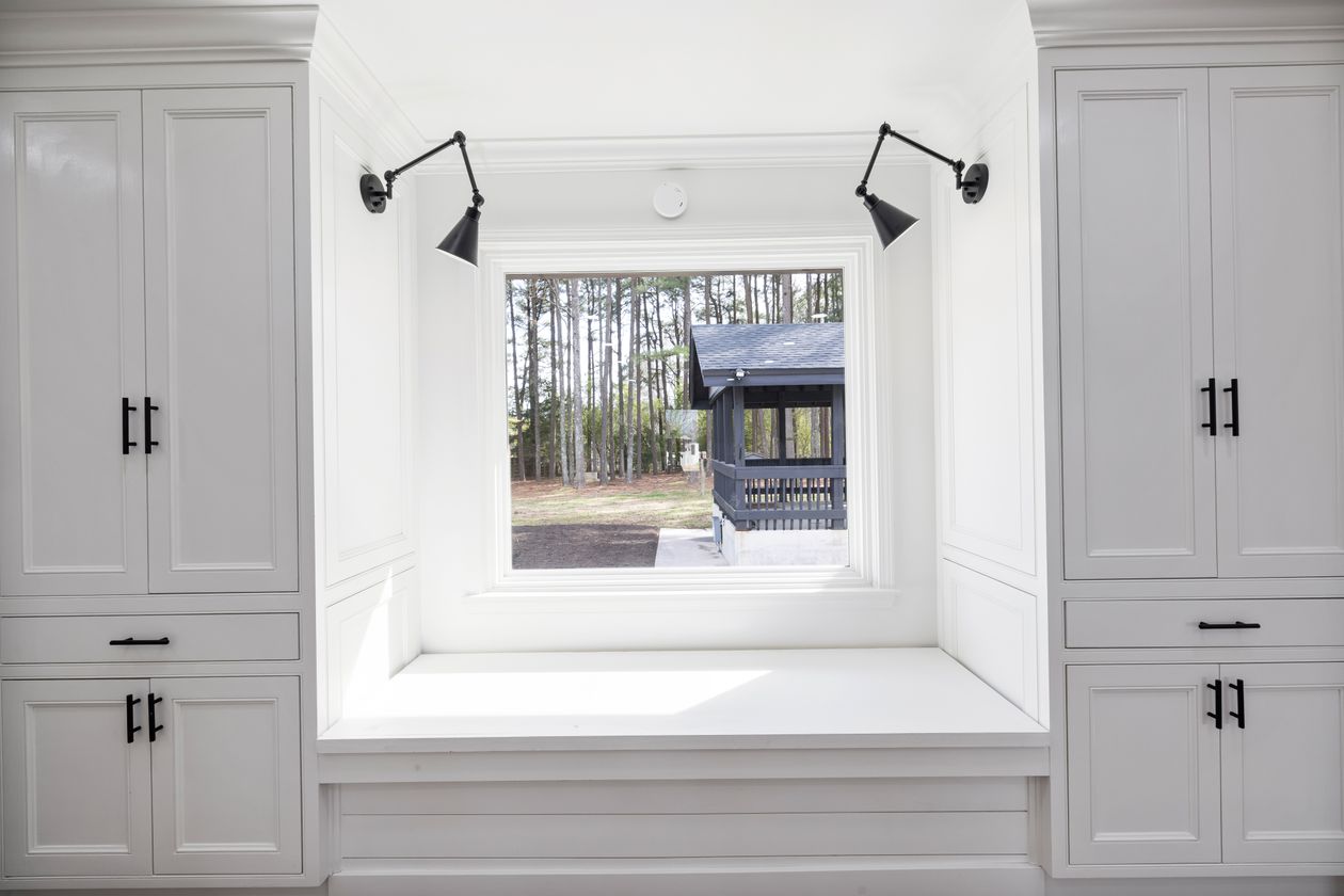 White built-in cabinets flanking a window seat with wall sconces