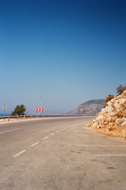 A winding coastal road with clear blue skies, perfect for travel photography.