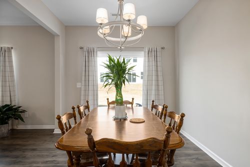 Free Elegant dining room featuring a wooden table, modern chandelier, and minimalist decor for a cozy ambiance. Stock Photo