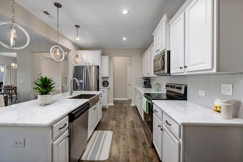 Free Beautiful modern kitchen featuring white cabinetry, marble countertops, and stylish pendant lights. Stock Photo