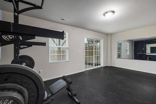 A well-lit, spacious home gym featuring modern weightlifting equipment and a large mirror.