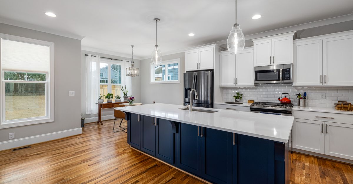 Spacious kitchen featuring white cabinetry and wooden flooring, perfect for modern homes.