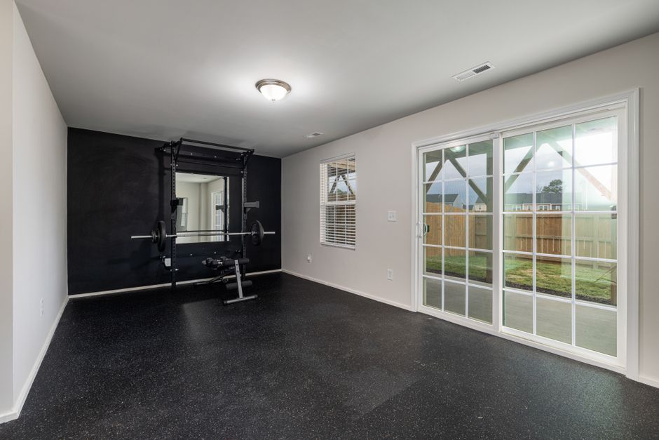 Spacious home gym featuring weightlifting equipment and a mirrored wall.