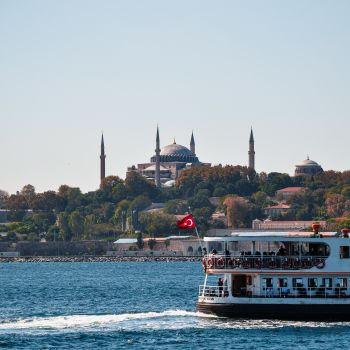 Scenic view of a ferryboat crossing Istanbul with the iconic Hagia Sophia in the background.