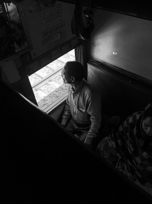 Free A man gazes out a train window in India, capturing a moment of contemplation. Stock Photo