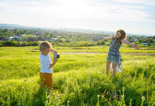 Free Two kids enjoying a carefree day in a sunny green field, capturing happy childhood moments. Stock Photo