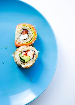 Colorful california sushi rolls on a blue plate, showcasing vibrant ingredients in a flat lay style.