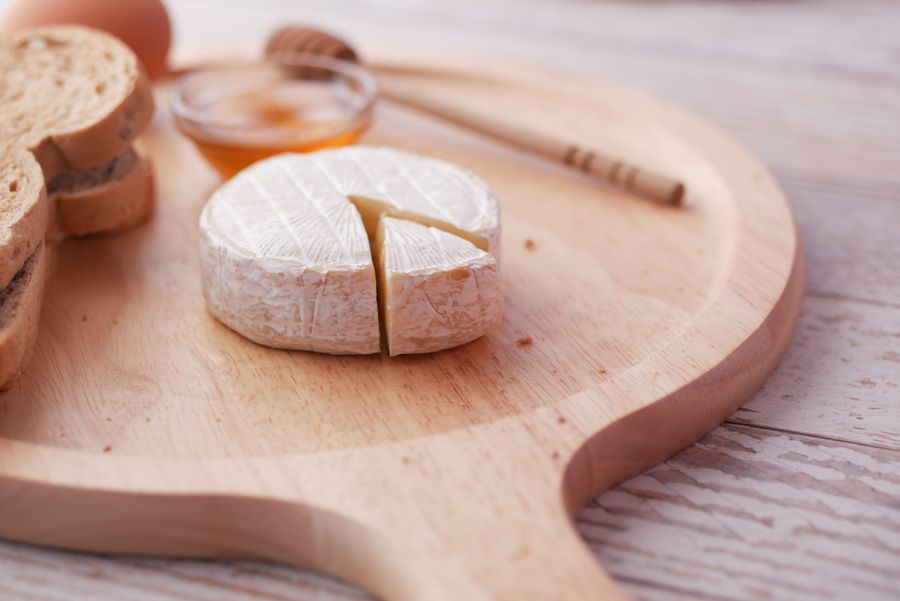 A creamy soft cheese cut open with bread and honey