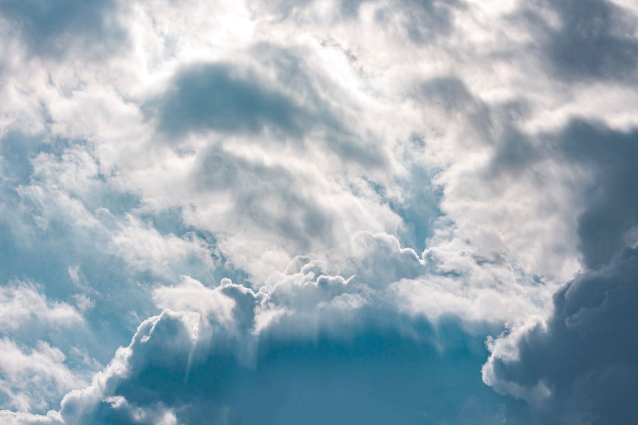 a dreamy and dramatic view of fluffy clouds in a bright blue sky over