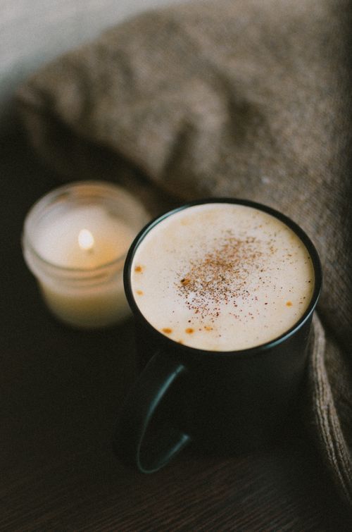 Free Warm cappuccino in a ceramic mug, with a lit candle on a wooden surface, creating a cozy atmosphere. Stock Photo
