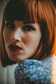 Close-up portrait of a woman with auburn hair and red lipstick, exuding a vintage vibe.