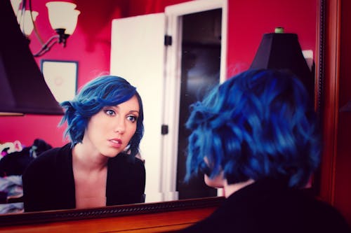 A Woman with Blue Hair Looking at Her Reflection