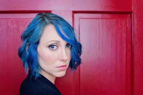 Woman with Blue Hair Standing next to a Red Door