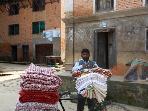 Free A man selling textiles on a bicycle in an urban outdoor setting. Stock Photo