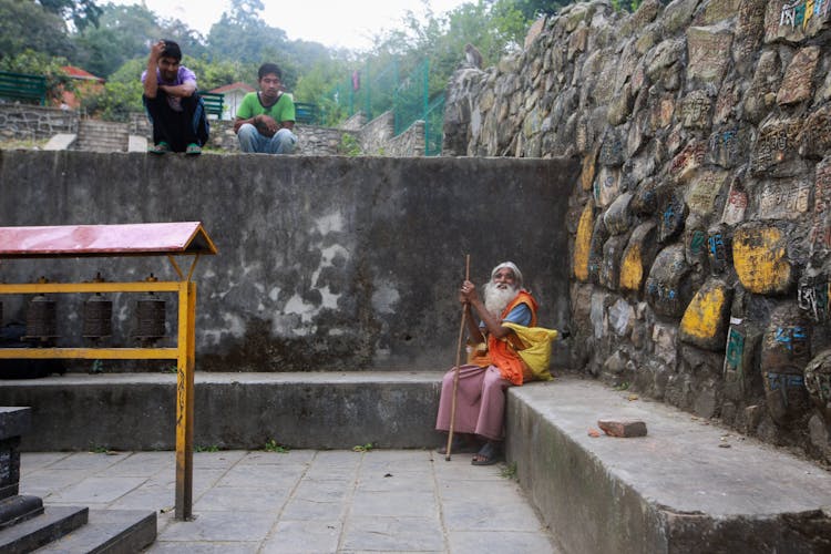 Hermit And Man Sitting Near Temple Bells And Walls