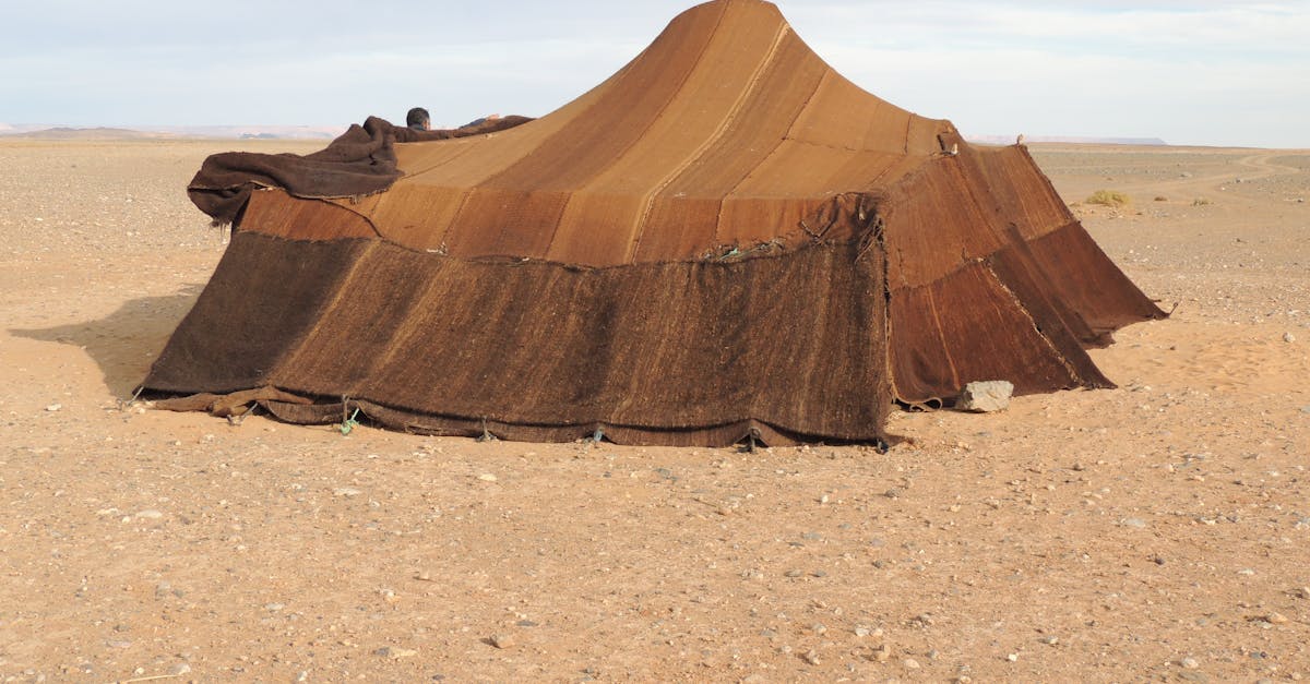 Brown nomadic tent set in a barren desert landscape under a clear sky.