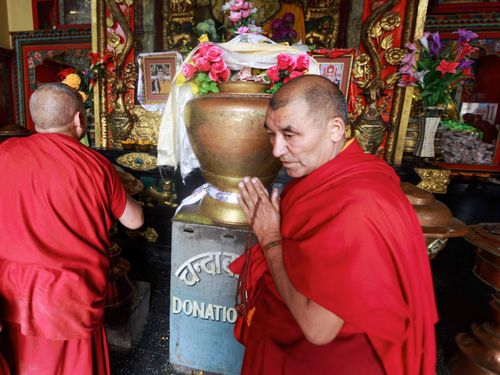 Free Buddhist monks in red robes engage in spiritual practices inside a vibrant temple. Stock Photo