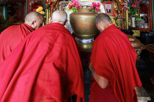 Free Three Buddhist monks in red robes are praying at a sacred altar inside a temple. Stock Photo