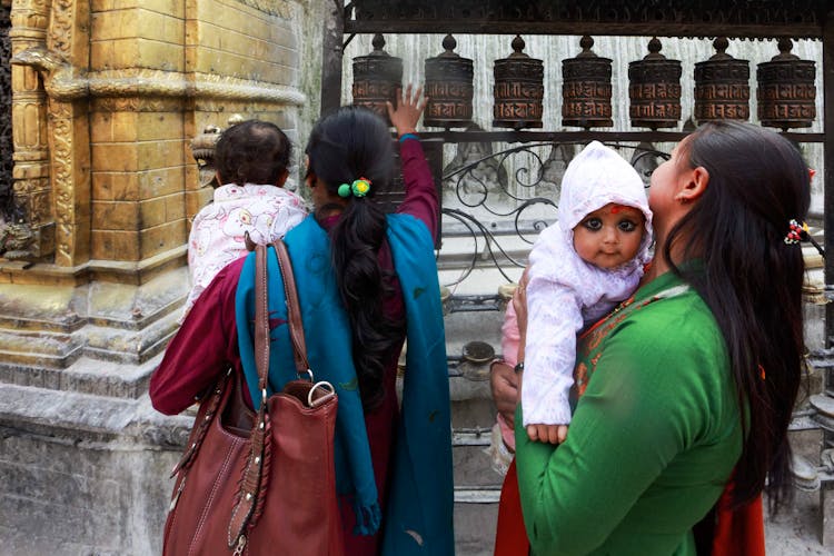 Women With Babies By Tibetan Prayer Bells