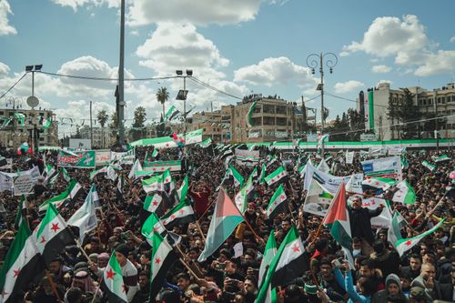 Free Crowd of people in a Syrian city square holding flags and banners during a peaceful demonstration. Stock Photo