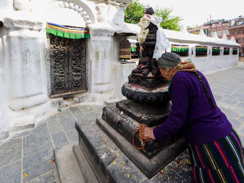 Elderly Woman praying before a Statue