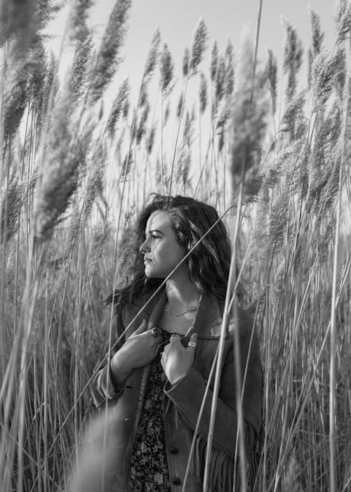 Grayscale Photo of Woman in Black Tank Top Standing on Grass Field
