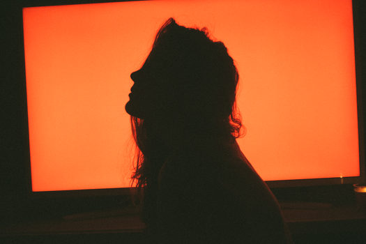 Artistic silhouette of a woman against a bright orange screen creating a dramatic contrast.