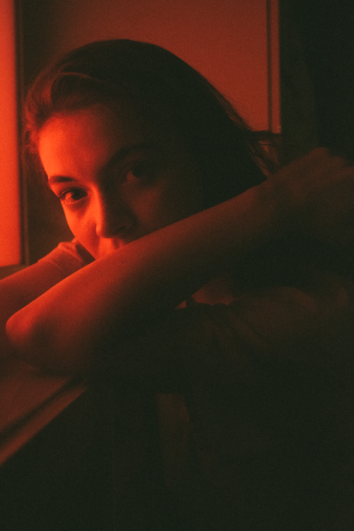 Free Artistic portrait of a woman in warm red light creating a moody ambiance. Stock Photo
