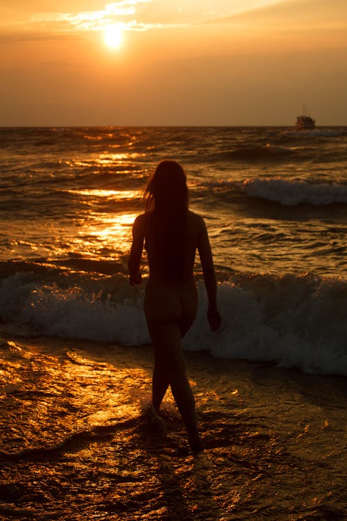 Woman Walking on Beach during Sunset