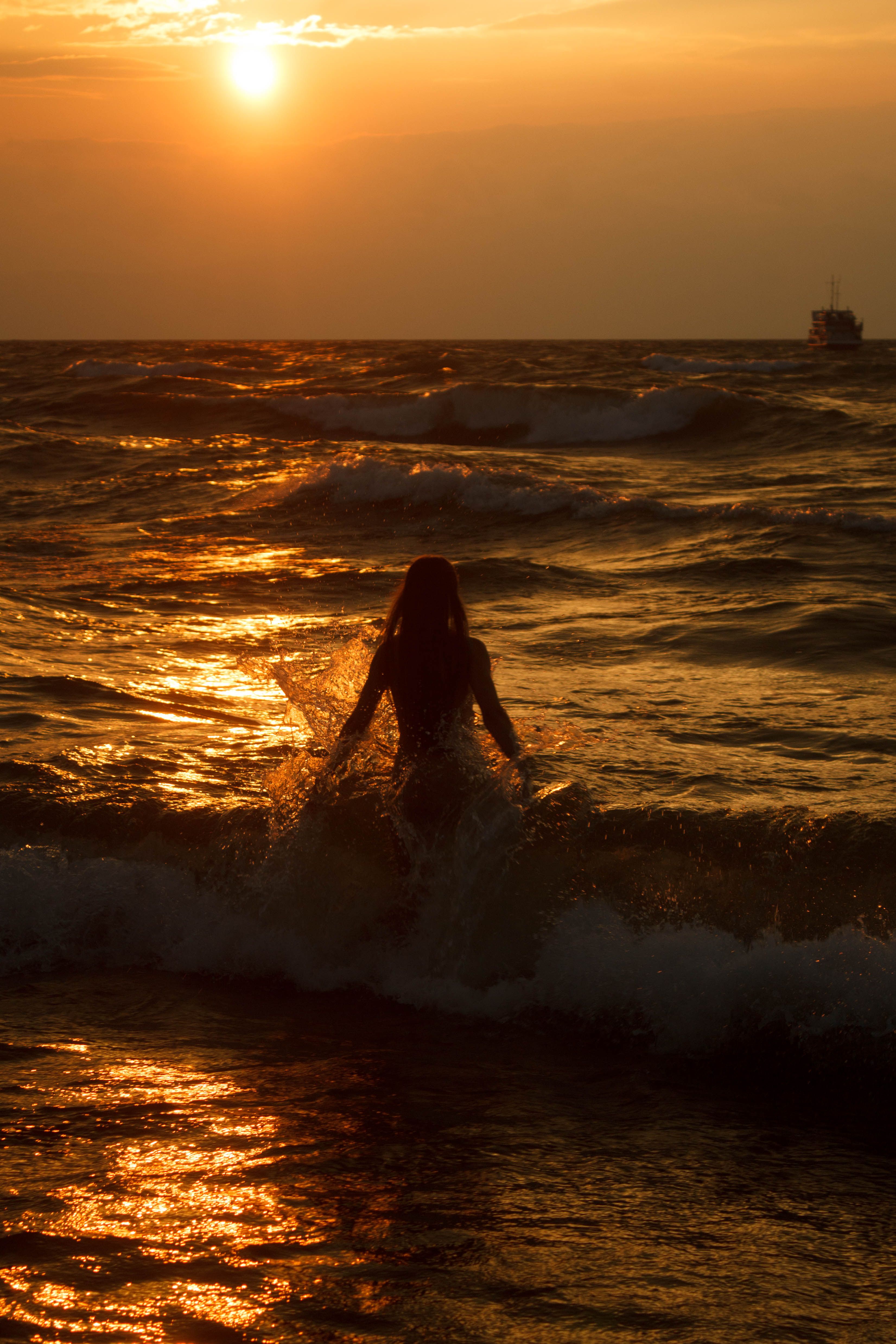 Woman Walking into the Sea at Sunset · Free Stock Photo