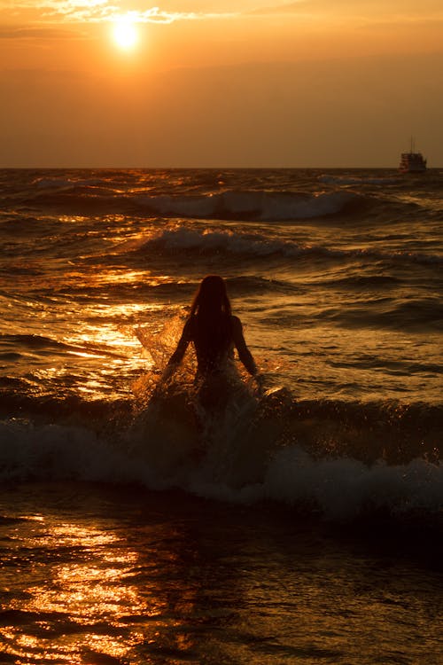 Woman Walking into the Sea at Sunset