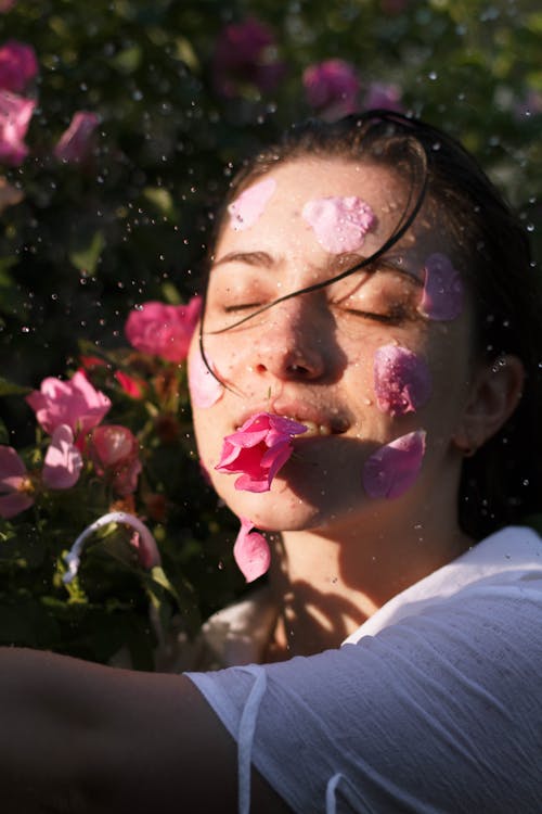 Woman in White Shirt With Pink Flower Petals on Her Face