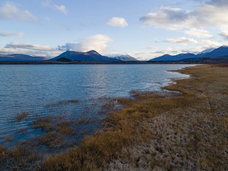 Beautiful lake with mountains in YT, Canada, under a blue sky.