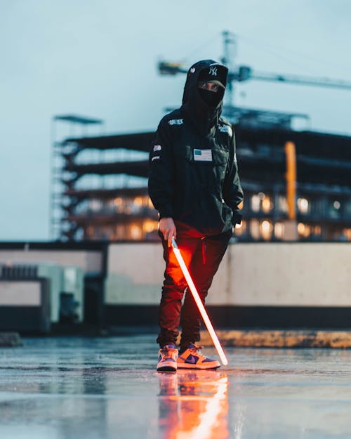 Stylish Man in Black Jacket and Red Pants Holding Red Neon Light Stick