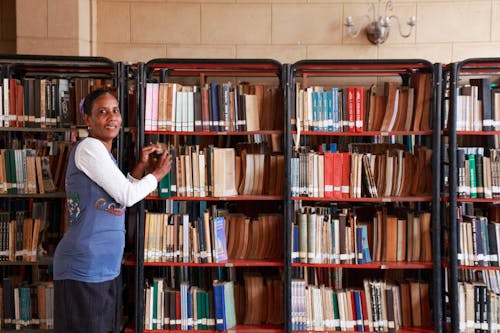 Woman standing beside Bookshelves 