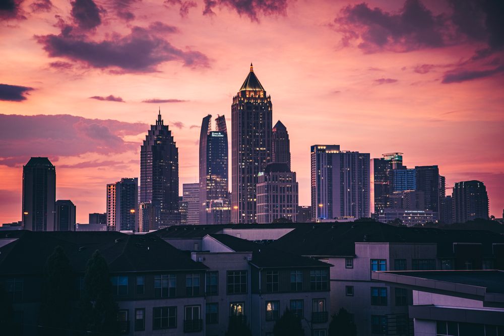 The Atlanta skyline under a picturesque pink sunset, featuring high-rise skyscrapers.