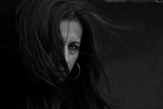 Dramatic black and white portrait of a woman with her hair covering part of her face.