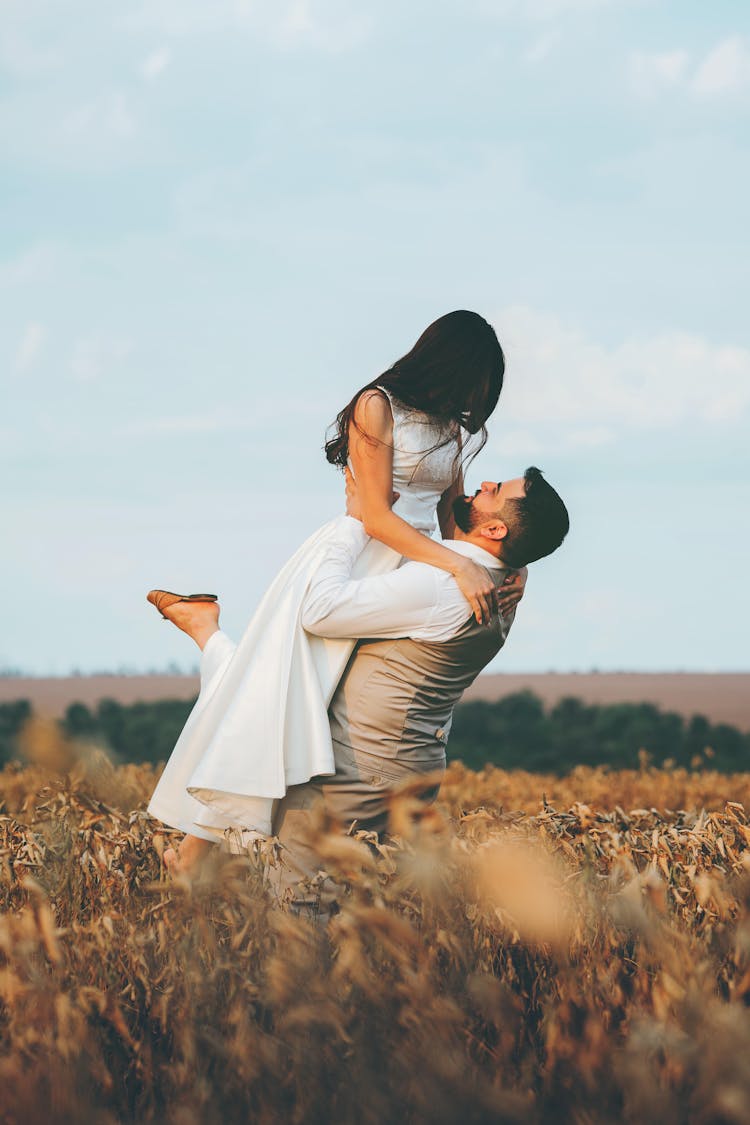 Man Picking Up Bride In Field